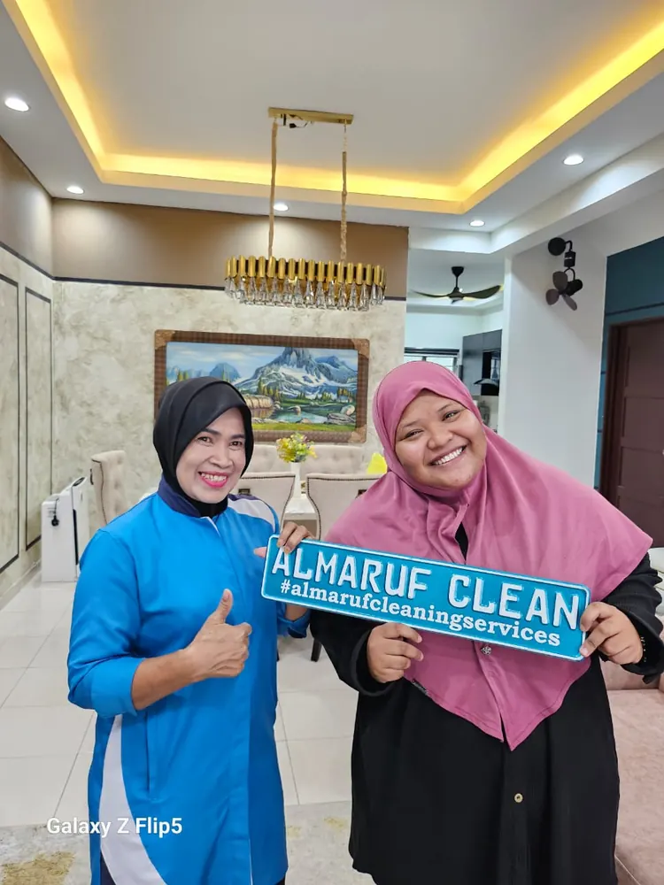 Almaruf Clean cleaner holding the Almaruf Clean sign with a customer after the job