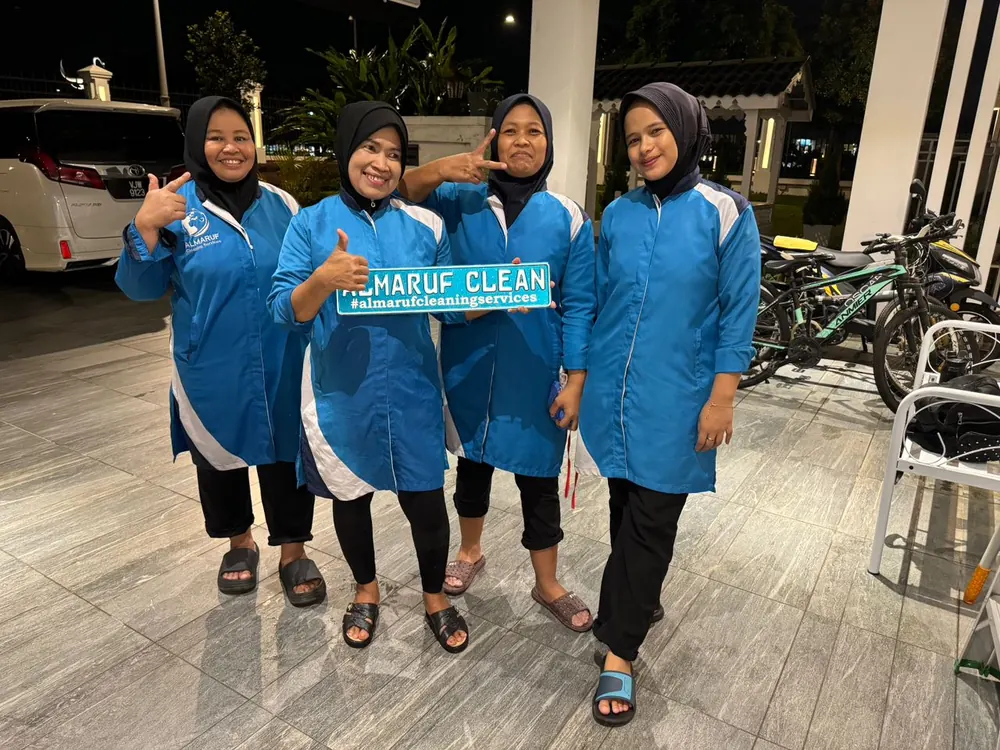 An Almaruf Clean team holding the Almaruf Clean sign at a customer's house in the evening